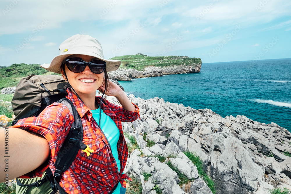 Φωτογραφία Happy woman backpacker traveler take a selfie photo on amazing ocean coast