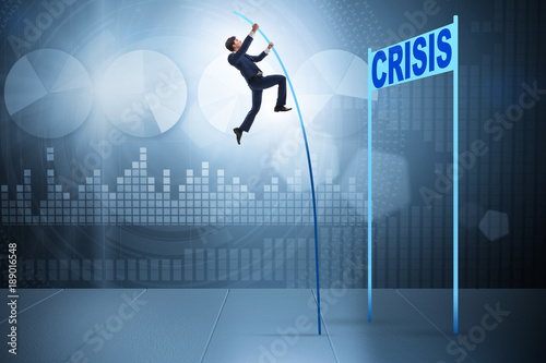 Businessman pole vaulting over crisis in business concept
