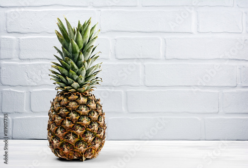 Fresh ripe whole pineapple on gray brick wall background