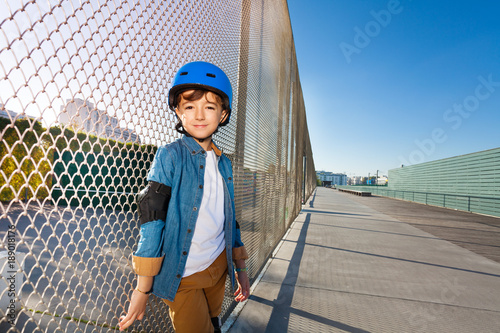 Happy boy in helmet standing at outdoor rollerdrom photo