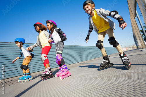 Fototapeta Naklejka Na Ścianę i Meble -  Happy kids rollerblading on the road at sunny day