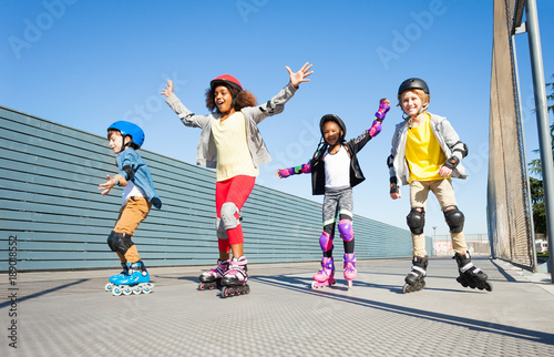 Joyful kids rollerblading outdoors at sunny day