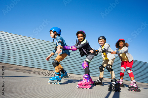 Cute kids rollerblading one after another outdoors