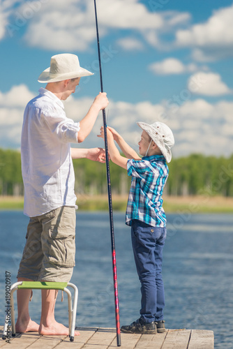 son helps his father to fish in the lake