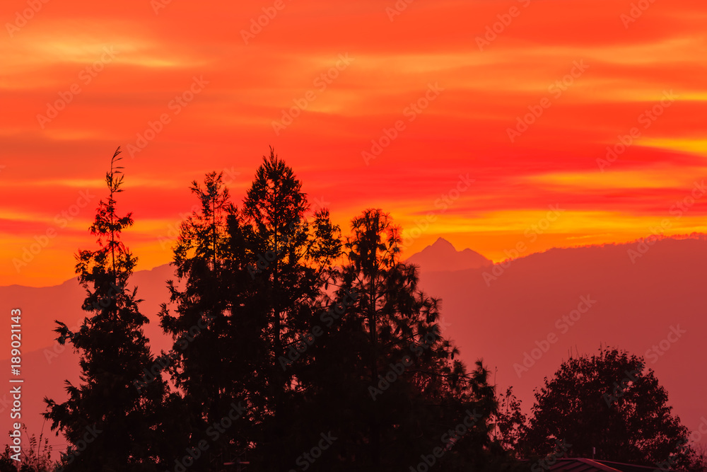 a spectacular sunset over the mountains paints the sky of pink, orange and yellow. /the sun was very low beyond  the horizon and its rays crossing the atmosphere increased the red color of the sky