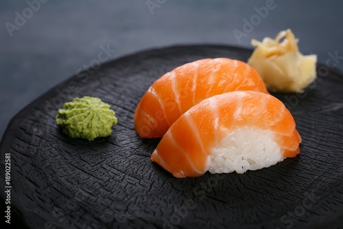 Delicious Japanese cuisine, nigiri sushi with salmon served with wasabi and ginger, close up. Sushi restaurant concept