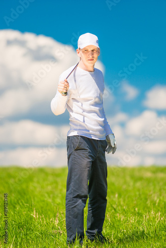 vertical portrait of a successful golfer with a golf club in the field