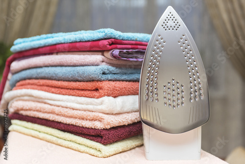 Electric iron and a stack of towels on the ironing board.