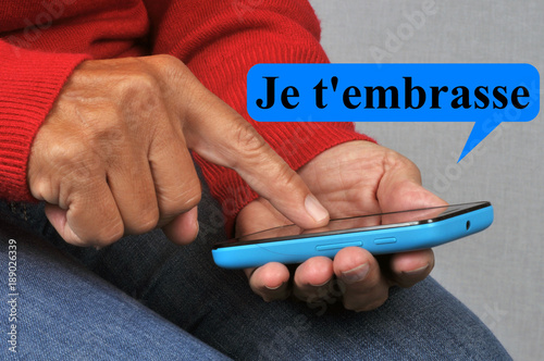 Personne envoyant un SMS avec un smartphone disant je t'embrasse photo