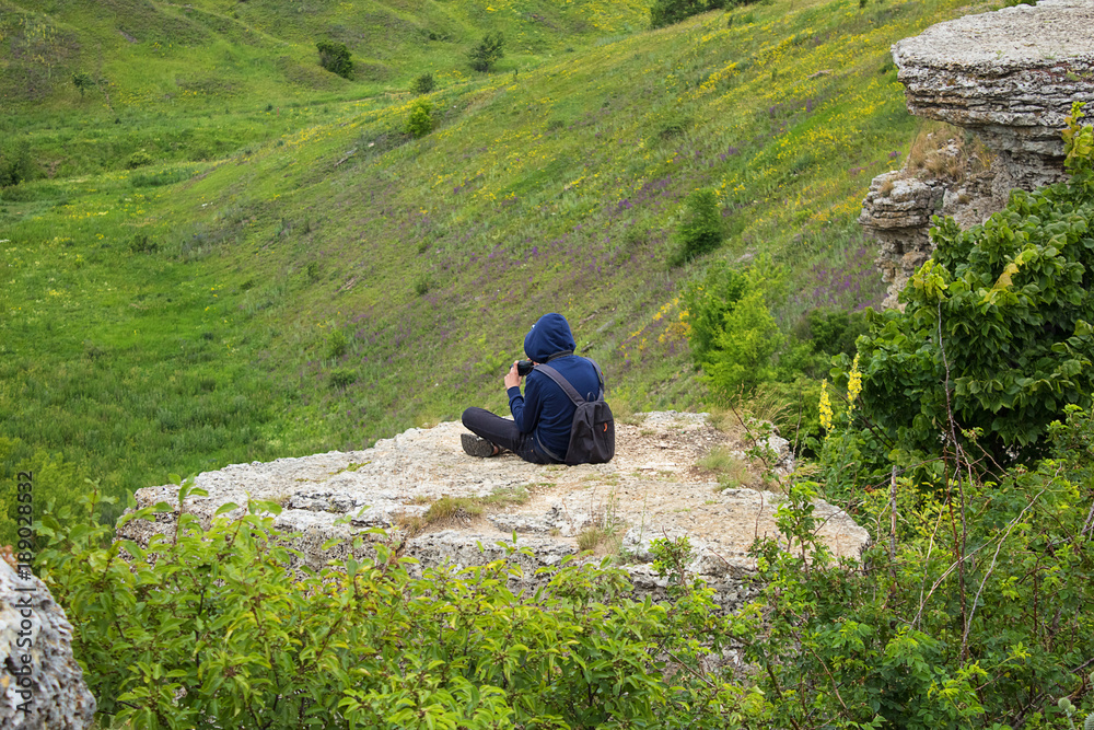A child, a teenager sits on the edge, on a cliff A child, a teenager sits on the edge, on a cliff