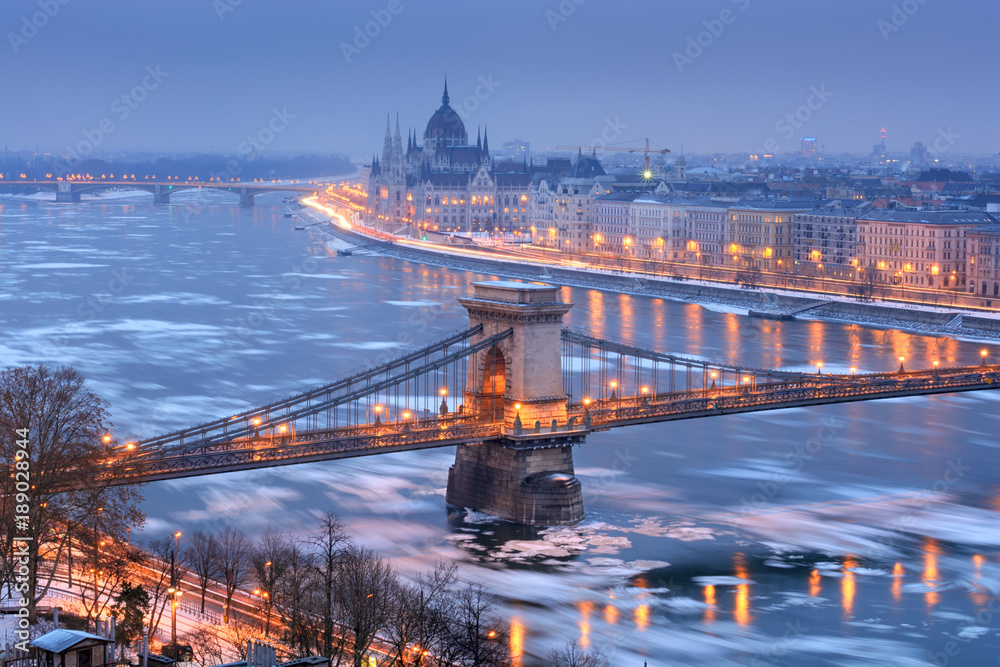 Szechenyi chain bridge and Pest riverfront with Parliament outline in winter night, Budapest