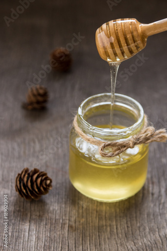 Honey pours with wooden sticks in a jar