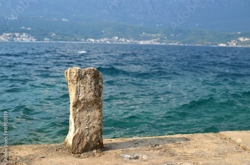 Old stone on a dock for binding boats and blue sea