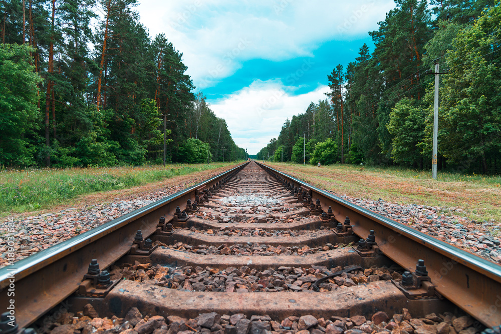Rusty railroad with rocks in the forest under light blue cloudy sky. Old railroad in poor country. Rusty railroad with rocks in the forest under light blue cloudy sky. Old railroad in poor country.