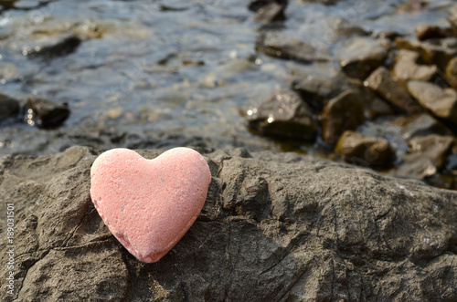 Pink bath salt figure in a heart shape on a sea rock