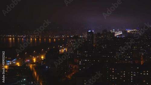 shooting night city. The lights are burning in the windows of apartment buildings. On the asphalt reflections glare from the passing cars. light is splashing in the water. lake or river. night Kiev