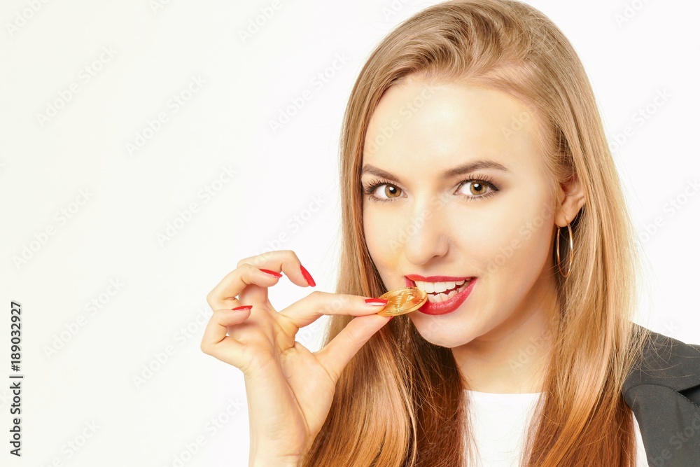 Pretty woman tasting a golden bitcoin coin on her tooth. Pretty woman tasting a golden bitcoin coin on her tooth.