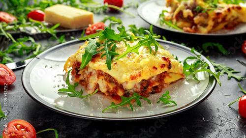 Homemade lasagna with minced beef bolognese and bechamel sauce topped wild arugula, parmesan cheese