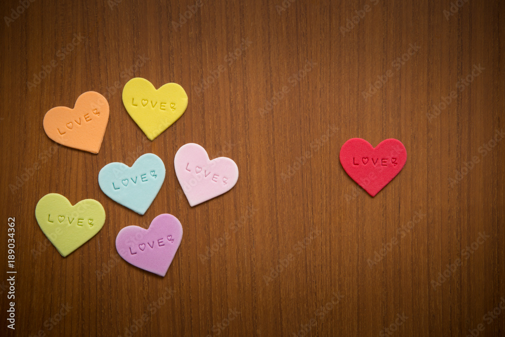 Fondant icing for cake decoration in heart shape of red, green, orange, purple, blue, white & yellow colours on dark brown wood background with copy space for text decoration, Valentines day concept Fondant icing for cake decoration in heart shape of red, green, orange, purple, blue, white & yellow colours on dark brown wood background with copy space for text decoration, Valentines day concept