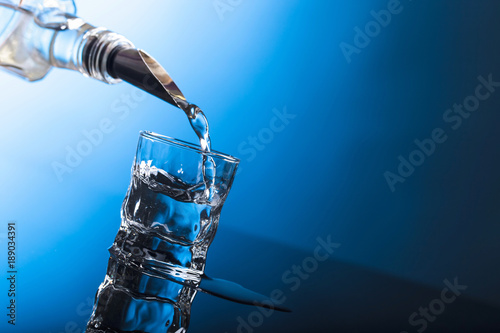 Vodka pouring from the bottle into  glass in a bar. Fototapeta
