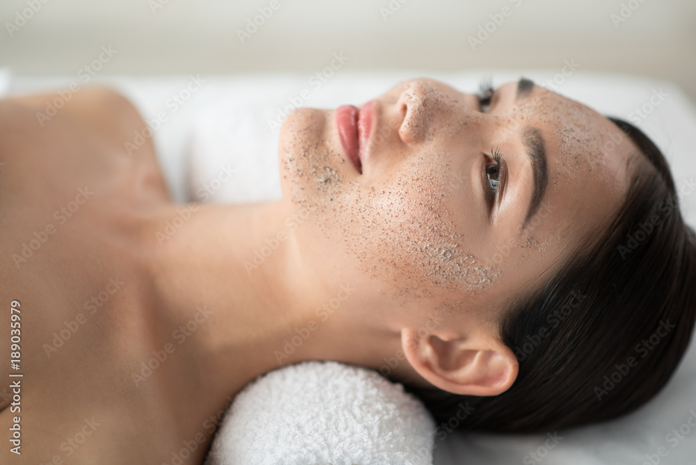 Peace and comfort. Close up of serene asian girl lying with scrub mask on her face at spa