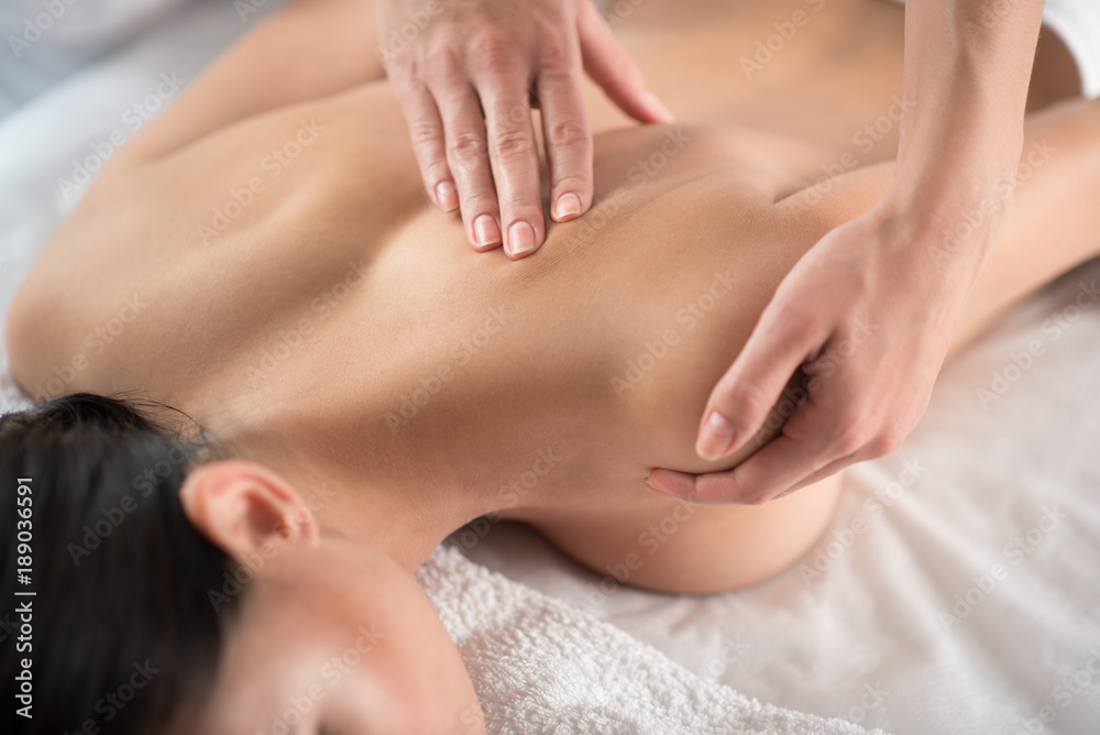 Close up of beautician arms pampering back of young woman. Healthy skin and body concept