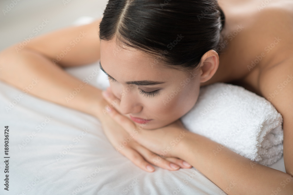 Top view of calm asian girl lying and sleeping on massage table at beauty salon. Close up Top view of calm asian girl lying and sleeping on massage table at beauty salon. Close up