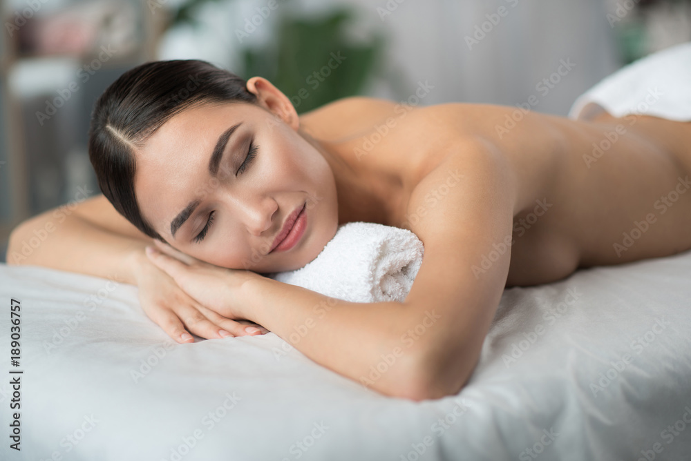 Portrait of satisfied young asian woman lying on massage table at spa. Her eyes are closed with relaxation Portrait of satisfied young asian woman lying on massage table at spa. Her eyes are closed with relaxation