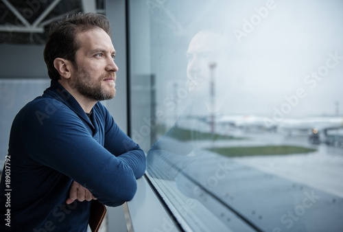 Thoughtful male person looking at the view from the window before boarding. Copy space in right side photo