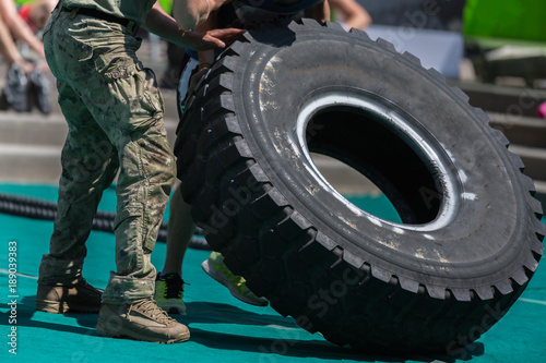Fototapeta Naklejka Na Ścianę i Meble -  Soldiers Lift Huge and Heavy Truck Tire