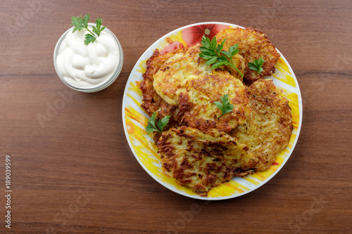 Homemade fried potato pancakes with sour cream on wooden table