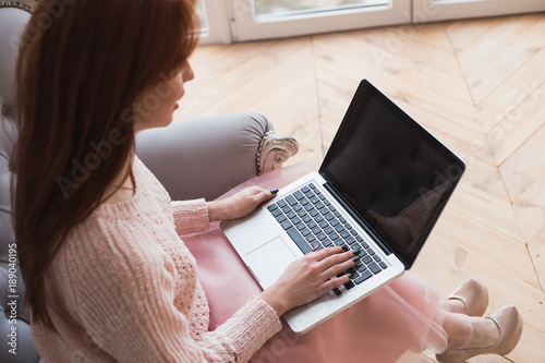 A nice young women is working on her laptop. The girl is searchi photo