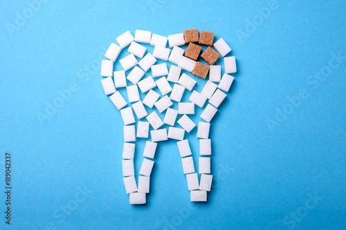 Sugar destroys the tooth enamel and leads to tooth decay. Sugar cubes are laid out in the form of a tooth and brown sugar symbolizes caries.