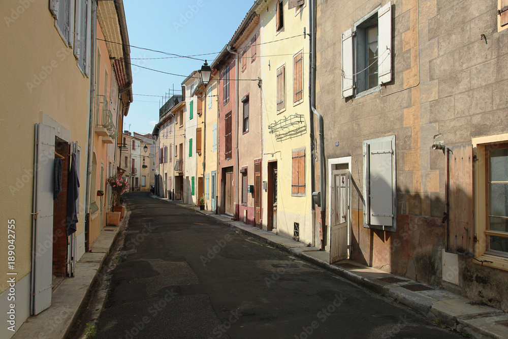 Multi-coloured row of cottages, situated along a deserted village street in the South of France