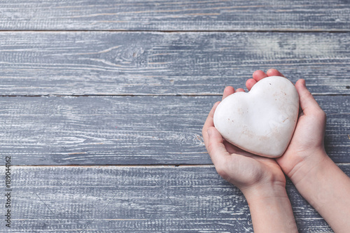 Children's hands hold cookies in the form of heart on a wooden table-top. Concept by the Mother's Day. Soft toning. Copy space