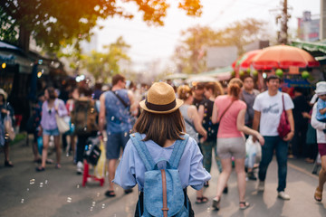 Young woman traveler with sky blue backpack and hat looking the way with in JJ Market in Bangkok Thailand. Traveling in Bangkok Thailand