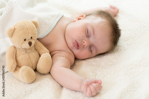 sleeping newborn baby with teddy bear