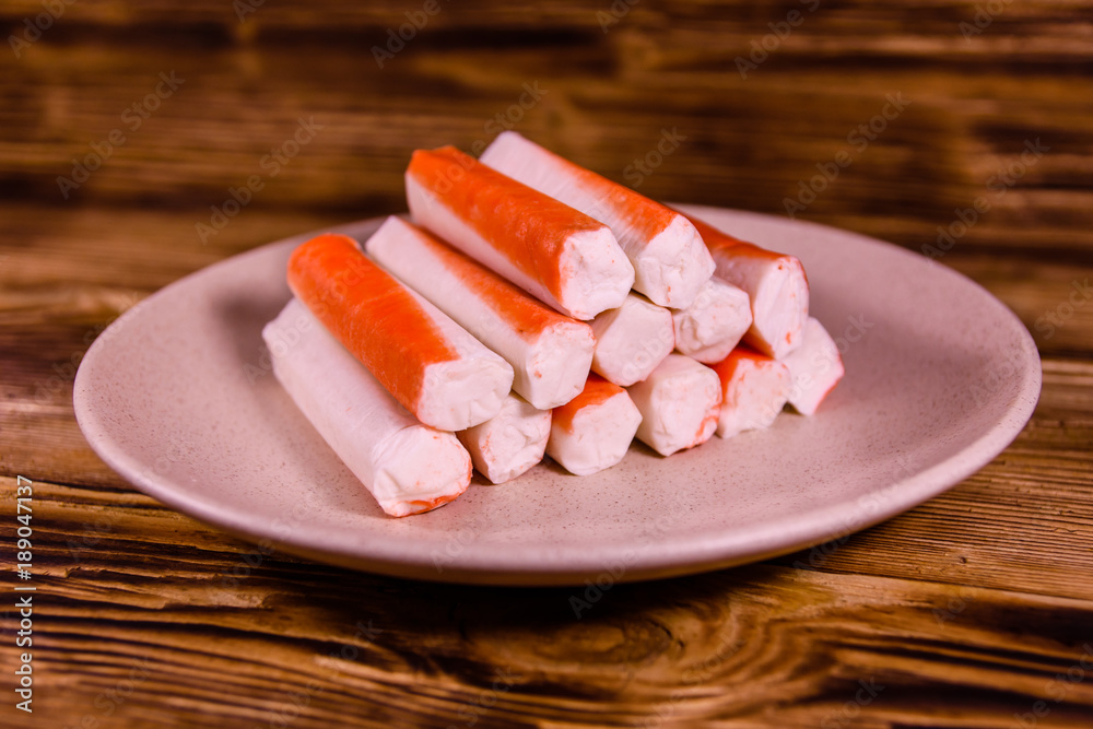 Ceramic plate with crab sticks on wooden table Ceramic plate with crab sticks on wooden table