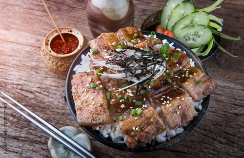 Grilled slice pork with charcoal flame set on rice bowl in Japanese style. photo