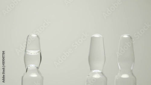 A man in blue latex gloves takes ampoules with a clear solution for injections. Close up view