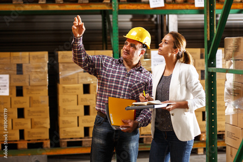 Manager and warehouse worker checking list and inventory on the shelf in storehouse.