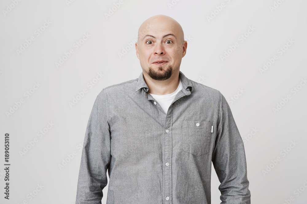 Portrait of bald mature man with beard looking surprised and amazed at camera while standing over white background. Adult wearing casual clothes, stunned. He did not expect to see his friend. Portrait of bald mature man with beard looking surprised and amazed at camera while standing over white background. Adult wearing casual clothes, stunned. He did not expect to see his friend.