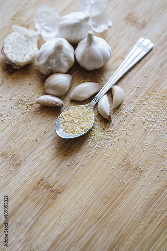 Garlic bulbs, cloves and garlic powder on a wooden background