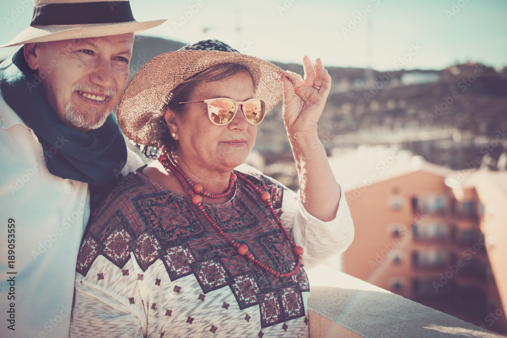 elderly senior in vacation with hats looking panorama from a rooftop