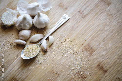 Garlic bulbs, cloves and garlic powder on a wooden background