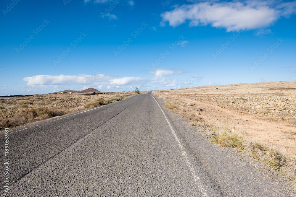 Travel on a long road in Fuerteventura with desert at both sides