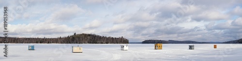 Panorama of wooden shelters for ice fishing on a frozen lake