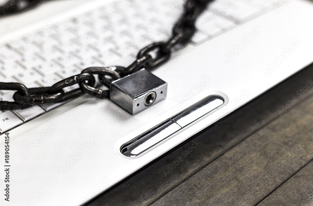 Heavy chain with a padlock around a laptop on gray table.
