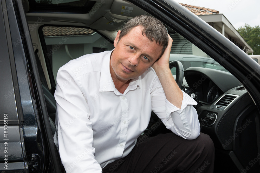 Attractive businessman man poses with his car