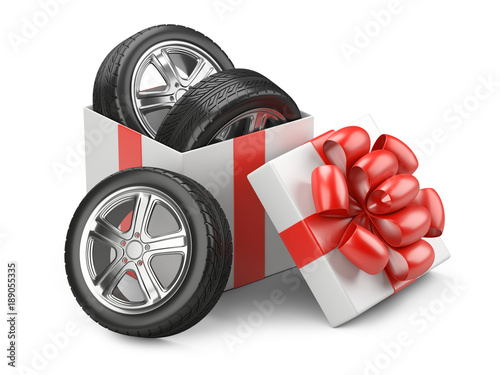 White open cardboard box gift with car tires whelles and red bow on a cap.